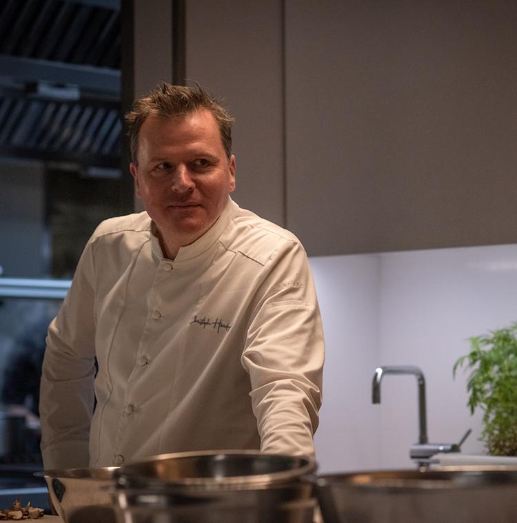 Christophe Hardiquest dans les cuisines de son restaurant Bon-bon avec une bouteille de BRU®