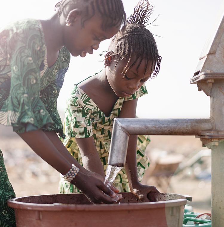 Kinderen pompen water uit een drinkwaterbron in Rwanda